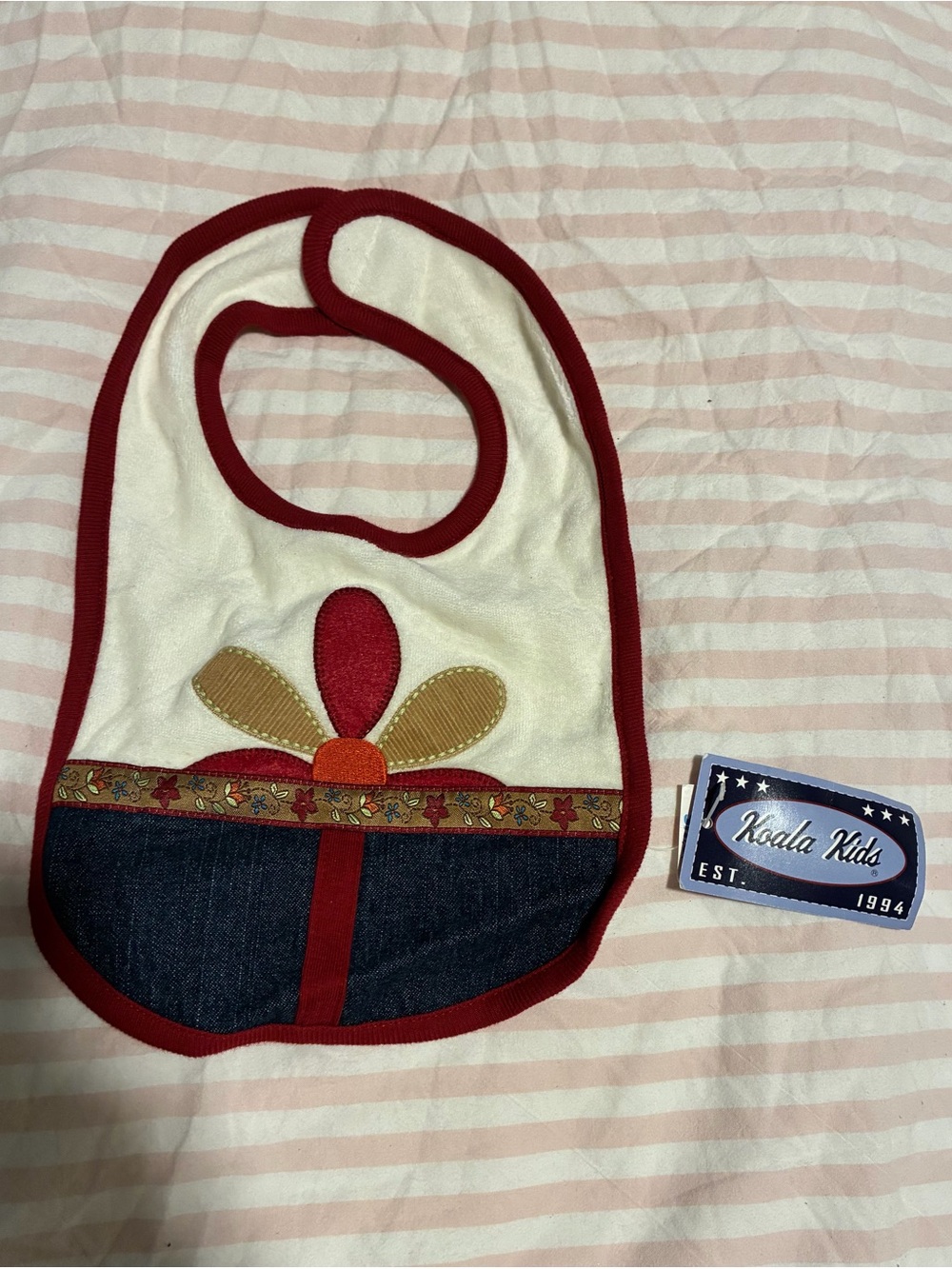 Koala Kids Cream Bib with Red Trim and Floral Patch